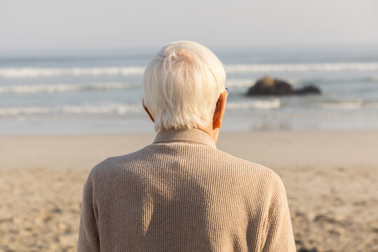 rear view of elderly man looking out at ocean waves, grotto beach, hermanus, South Africa
