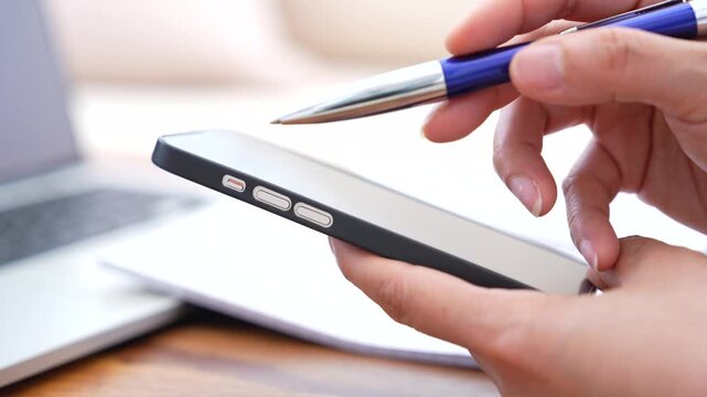 Person checking financial information on smartphone, Taking notes, Reviewing data on laptop. Online tax filing,Accounting workflow,Business documentation,Expense tracking, Financial planning