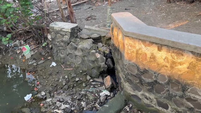 Damaged concrete drainage ditch and collapsed stone retaining wall
