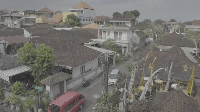 Aerial high angle view of Bali residential area with traditional houses, penjor decorations, and red minivan during Galungan festival, Indonesia