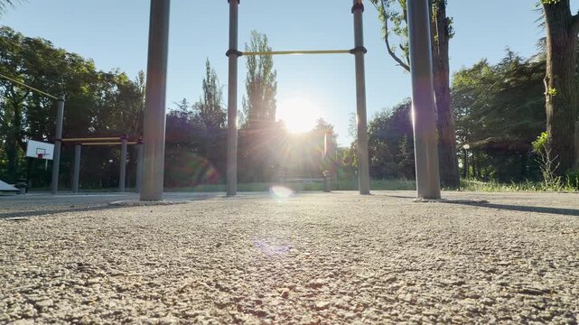 workout structures stand empty under a bright, sunny sky. Beautiful sunbeams fill the peaceful green park, inspiring a powerful sense of fresh morning energy.