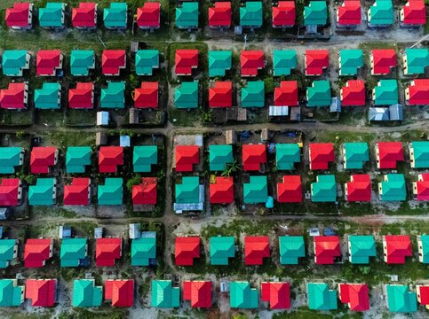 Joygonj, Bangladesh - 17 June 2026: Aerial view of rows of small houses with vibrant red and green roofs arranged in a neat grid pattern in a residential neighborhood.