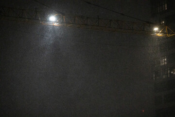 snow under the light of a construction crane at night