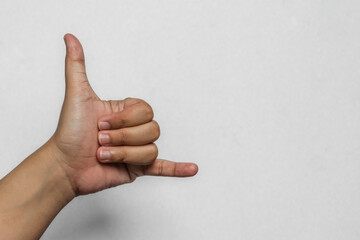 An Asian woman's hand showing the call me or shaka gesture on a white background. Concept of communication, contact us, and surfing culture. © Muhammad Azhar