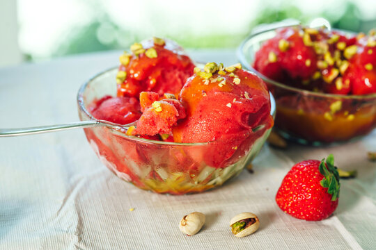 Close-up of strawberry sorbet with spoon in a glass dessert bowl. Refreshing homemade summer treat