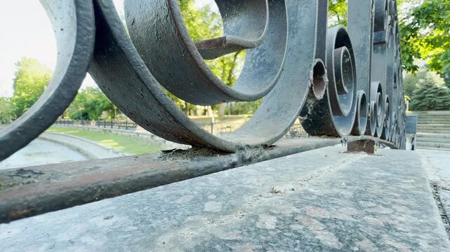 A close-up iron railing stands above a quiet river park in Simferopol, Crimea. This beautiful view evokes deep feelings of peaceful nostalgia. The sunny day feels perfectly serene.