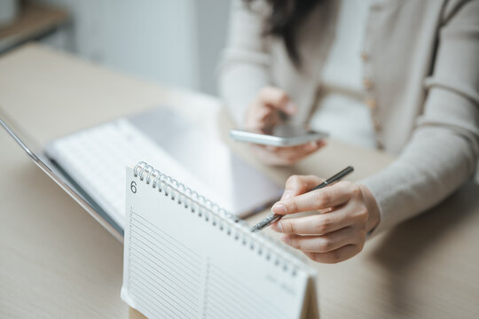 Person reviewing a calendar and smartphone to track bill payments, monthly expenses, and financial commitments, highlighting budgeting, invoice management, and payment reminders.