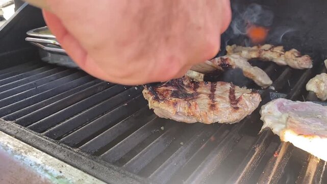 Hand wendet Fleisch auf dem BBQ-Grill. Authentisches Grillmotiv f&uuml;r Steakzubereitung, R&ouml;staromen, Barbecue, Outdoor Cooking, Grillmeister und sommerlichen Genuss.