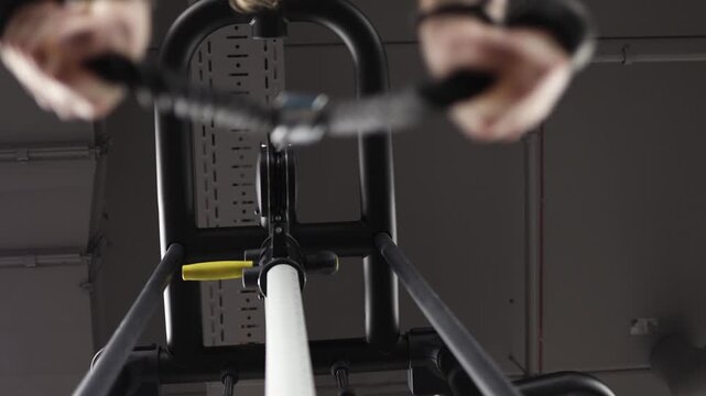 Low angle view of woman performing cable row exercise in modern gym focused strength training controlled movement fitness routine and upper body workout form
