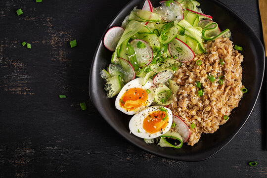 Healthy Breakfast Bowl with Oatmeal Salad and Soft Boiled Eggs. Above