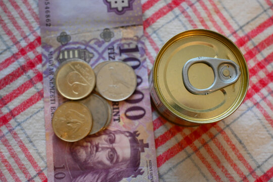 Close-up of canned liver p&acirc;t&eacute; next to Hungarian forint money, representing cost of living crisis, cheap food and financial pressure.