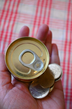 Close-up of canned liver p&acirc;t&eacute; next to Hungarian forint money with hand, representing cost of living crisis, cheap food and financial pressure.