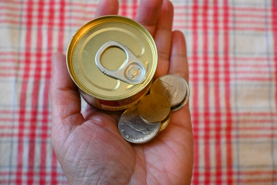 Close-up of canned liver p&acirc;t&eacute; next to Hungarian forint money with hand, representing cost of living crisis, cheap food and financial pressure.