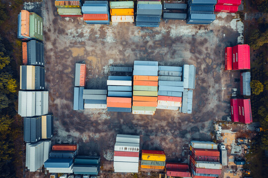 Warsaw, Poland - 15 September 2024: Aerial view of colorful cargo containers stacked in a logistics terminal surrounded by autumn trees.