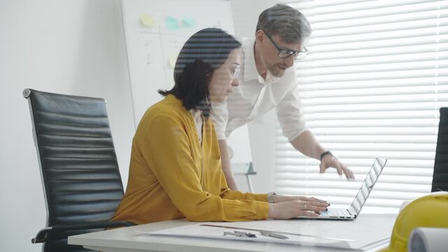 Architects and construction planners collaborating over blueprints and digital plans, using tablets, tools and whiteboard to draft and review building designs in a modern office setting