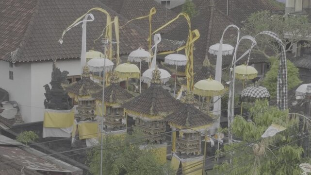 Close up high angle view of Balinese meru shrines whit yellow white tedung umbrellas, poleng cloth, and penjor decorations during Hindu ceremony Bali Indonesia