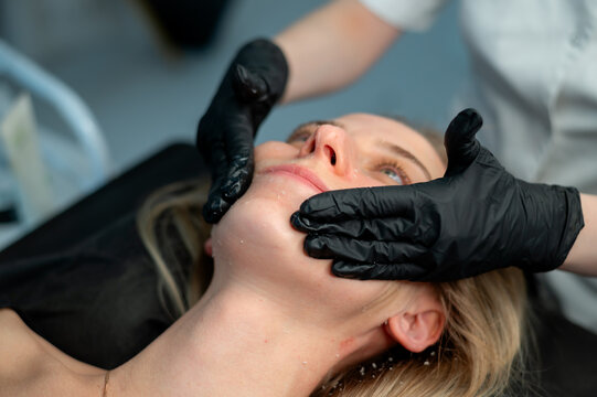 Professional facial peeling procedure performed by a cosmetologist in a beauty salon. Exfoliation of dead skin cells, deep cleansing, skin renewal, aesthetic cosmetology and anti-aging skincare concep