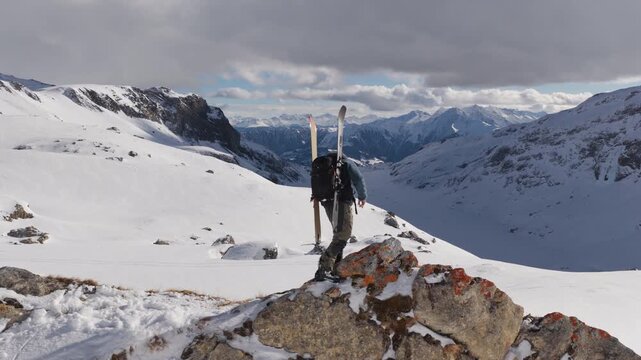  4K 59.94fps Cinematic drone orbit around a ski mountaineer on a rocky summit in Flims Laax, Swiss Alps, surrounded by rugged alpine terrain and snow-covered peaks.