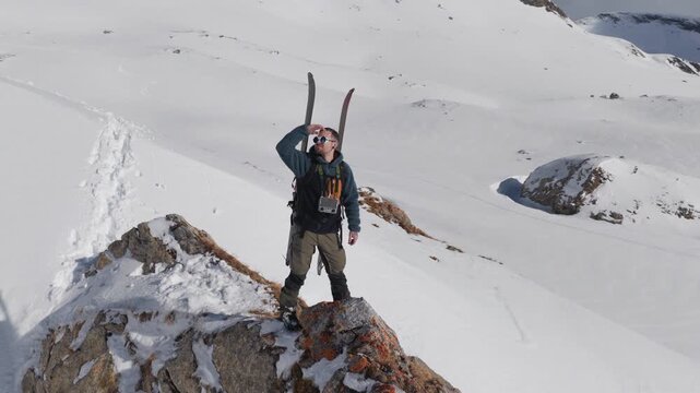  4K 59.94fps Cinematic drone orbit around a ski mountaineer on a rocky summit in Flims Laax, Swiss Alps, surrounded by rugged alpine terrain and snow-covered peaks.