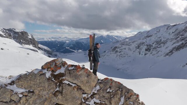  4K 59.94fps Cinematic drone orbit around a ski mountaineer on a rocky summit in Flims Laax, Swiss Alps, surrounded by rugged alpine terrain and snow-covered peaks.