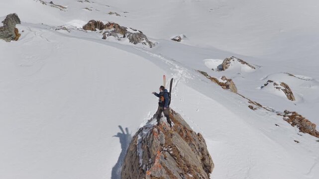  4K 59.94fps Cinematic drone orbit around a ski mountaineer on a rocky summit in Flims Laax, Swiss Alps, surrounded by rugged alpine terrain and snow-covered peaks.