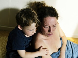 Obraz premium Young boy comforting his distressed mother in a quiet home setting for family support and emotional wellbeing lifestyle content