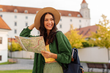 Woman touring city with map in hand while looking aside and smiling