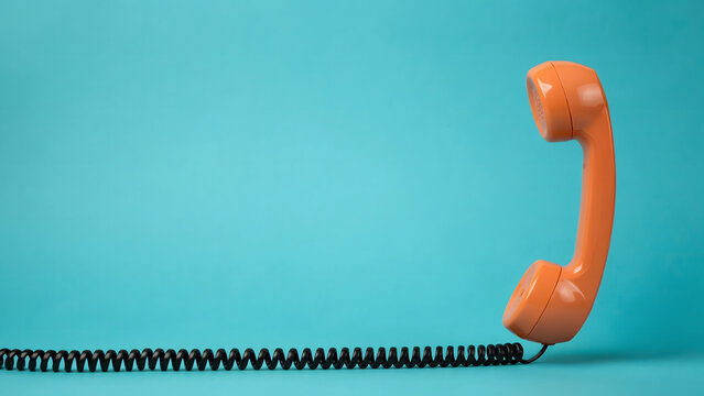 A vintage orange telephone handset resting on a vibrant blue background