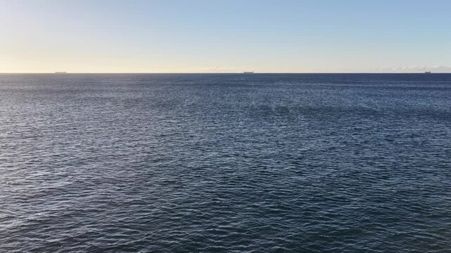 Back aerial flying over open sea off Australian pacific coast calm surface of the ocean.