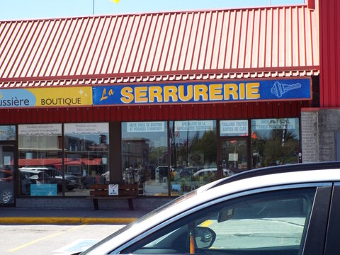 Gatineau,Quebec, Canada &ndash; May 15, 2026: A local locksmith shop named "La Serrurerie" features a bright storefront with service signage and a metal roof at 725 Bd de la Carri&egrave;re.
