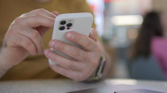 Close-up of hands using smartphone. Fingers tap screen with focus. Background shows blurred indoor setting. Person appears calm and focused. Suitable for tech, communication, or digital life themes