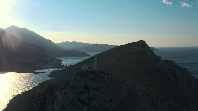 Aerial view of Knidos Lighthouse (Deveboynu) with a Turkish flag on a rocky peninsula at sunset, Datca, Turkey.