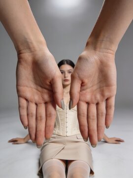 Artistic studio photograph capturing calm woman with precise hand framing and couture details