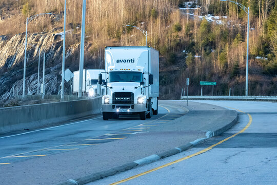 Quebec, Canada, 24 April 2026 : A white Mack semi truck with Avanti branding drives on a highway next to a rocky, forested hillside.