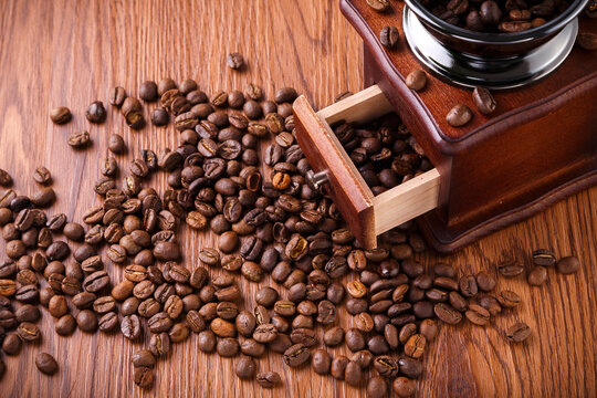 Roasted Coffee Beans and Vintage Manual Grinder on Wooden Table