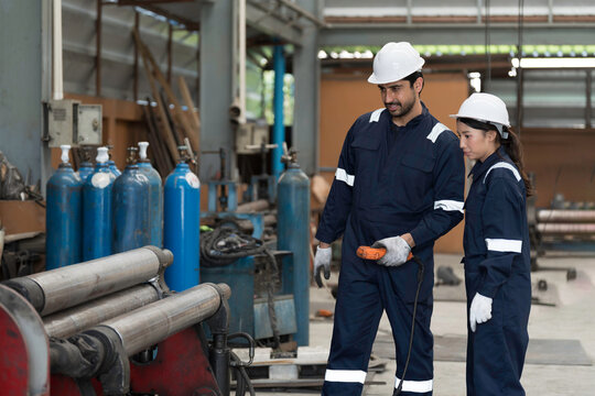 Factory and manufacturing machine. Male and female engineer at work, discuss during working with roll plate bending machine for manufacturing