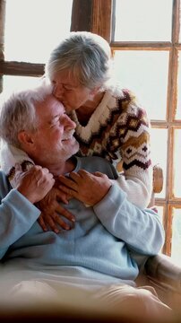 Senior people at home in love kissing and caring each other. Happy relationship mature man and woman together. Old male sitting on the couch and aged woman hugging him with care