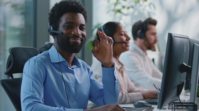 African American business man with headset working in call center showing okay gesture ok hand sign businessman looking at camera smiling in callcenter near multiethnic business team three workers