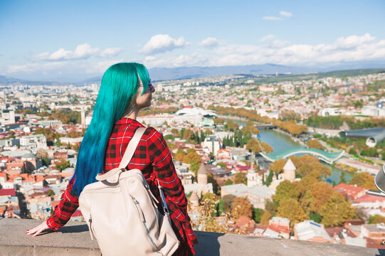 Traveler woman overlooks Tbilisi panorama beside river