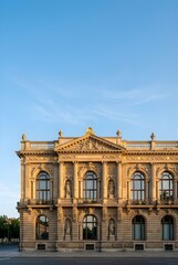Naklejka premium Classical ornate building facade with statues under blue sky at sunset