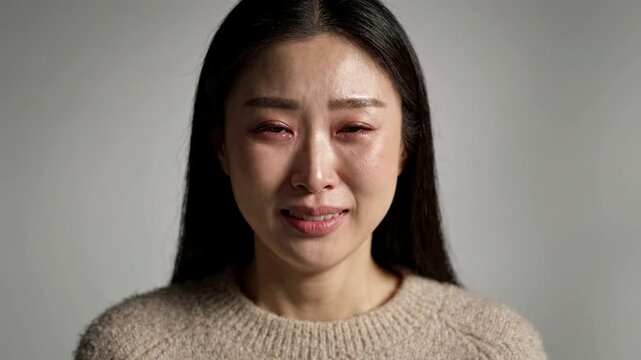 Emotional Asian Woman Cries and Smiles with Tearful Eyes Expressing Complex Feelings