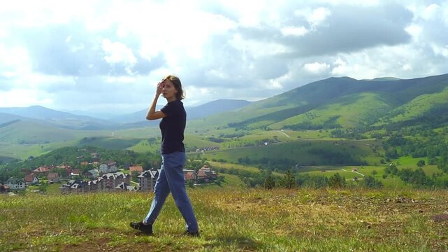 Woman pauses at Monument viewpoint in Zlatibor and observes broad mountain valley panorama. Represents reflective outdoor wellbeing, restorative scenery exposure, and perspective-seeking leisure.