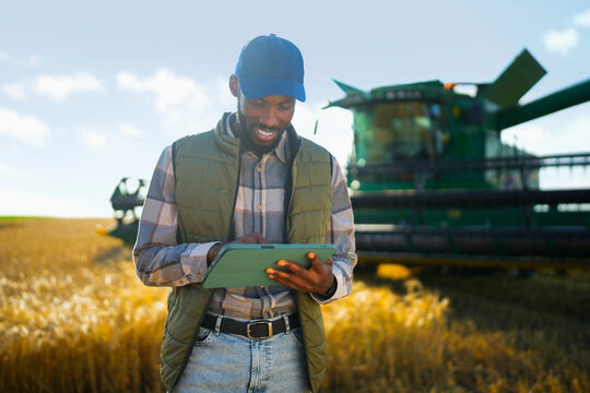 Farmer using a tablet in a wheat field to monitor farm operations and agricultural performance.
