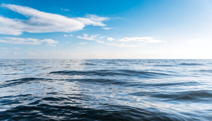Obraz premium Calm Ocean Waves Under Clear Blue Sky with Soft Clouds Scattered Horizon View