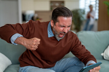 Fototapeta premium Angry man yelling, screaming in frustration at tablet