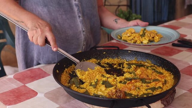 Mujer sirviendo una paella valenciana 