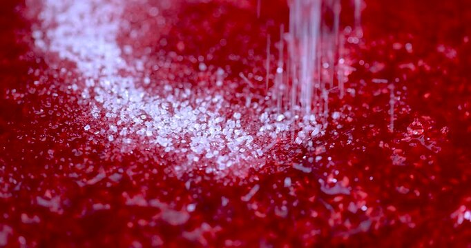 Red grated raspberries are sprinkled with white sugar, sweet granulated sugar is mixed with grated raspberries during dessert preparation.