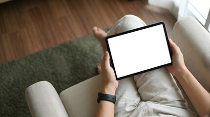 Naklejka premium Person holding a tablet with white blank screen while sitting comfortably on a soft chair