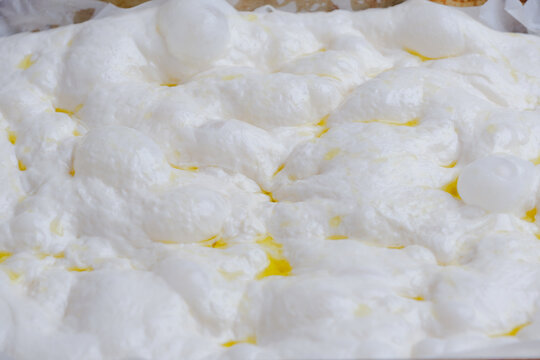 Naturally fermented sourdough focaccia dough during the final proofing stage. The dough surface is filled with air bubbles artisan bread-making process and traditional natural leavening techniques.