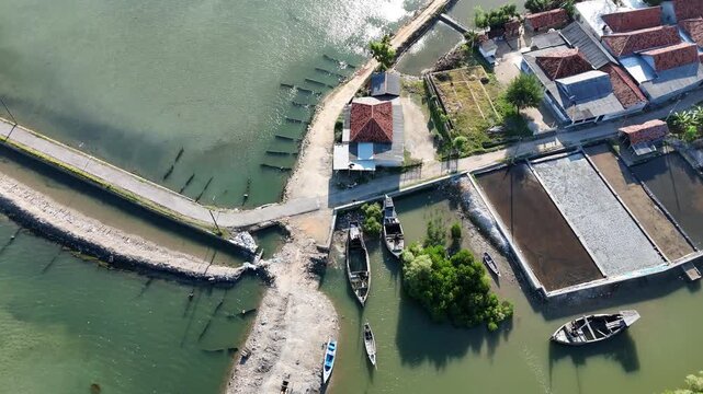 Top down aerial view of a traditional fishing village with wooden boats moored on the coast